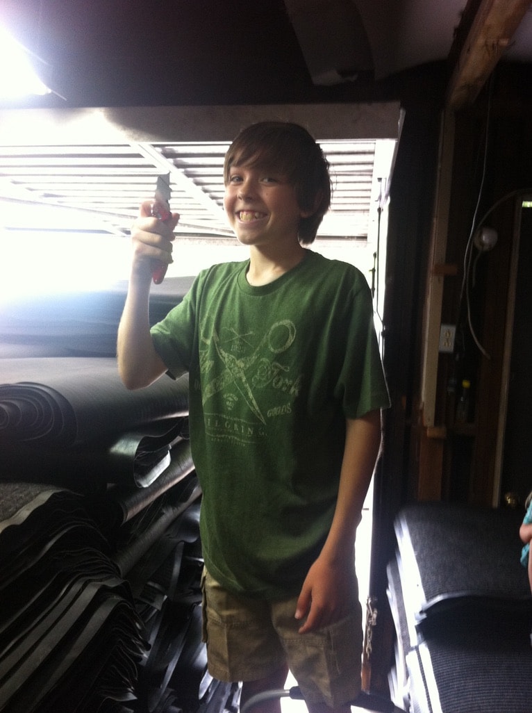 Kid in Mat Men warehouse holding a tool and smiling