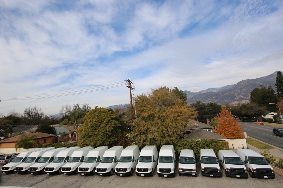 Mat Men fleet of white vans lined up with mountain backdrop